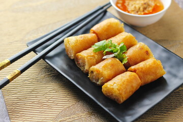 Fried Egg Rolls, Vegetable Rolls, Fried chinese spring rolls with sweet chili sauce served in a black plate in a restaurant.