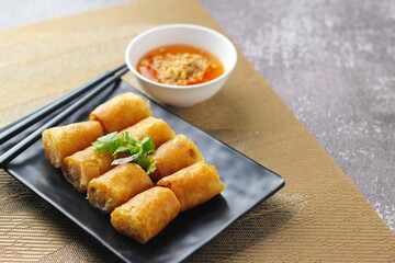 Fried Egg Rolls, Vegetable Rolls, Fried chinese spring rolls with sweet chili sauce served in a black plate in a restaurant.