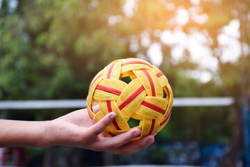 Young southeast asian male sepak takraw player using his right hand  to hold ball before sending to...