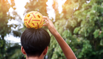 Young southeast asian male sepak takraw player using his right hand  to hold ball on his head,...