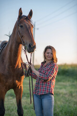 Obraz premium Portrait of a young beautiful girl in a field next to a horse.
