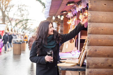Happy woman buys gifts at festive Christmas market. Concept of winter holidays.