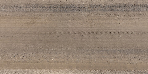 top view of surface of gravel road made of small stones and sand with traces of car tires