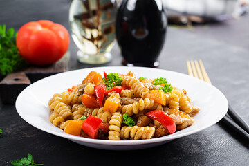 Vegetable pasta fusilli corti bucati with eggplant, sweet pepper and chicken in white plate on dark...