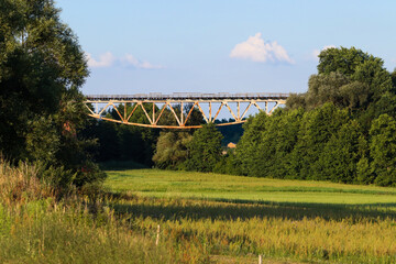 Stary most kolejowy między polami w letnim słońcu