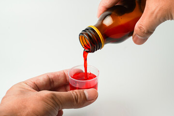 health concept, man and medicine concept - pouring medicine or antipyretic syrup from bottle into...