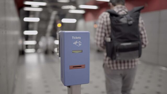 A man validating a ticket in a machine for validation of a transport system in Munich, Germany. Public transportation service. Person inserts paper ticket into validator machine for a time stamp. 