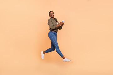 Fototapeta na wymiar Full body portrait of crazy carefree girl jumping hold use telephone isolated on beige color background