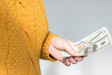 Close-up of a woman's hands in a yellow sweater counting bills of money, dollars. The concept of...