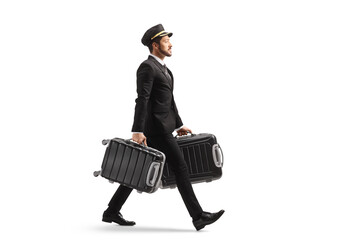 Full length profile shot of a bellboy walking and carrying two suitcases