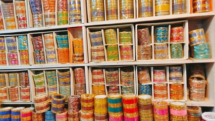 Fototapeta na wymiar In an Indian shop, a closeup of a wide variety of bangles displayed, including those made of glass, metal, and lac, in both shiny and matte finishes, commonly worn by females. 