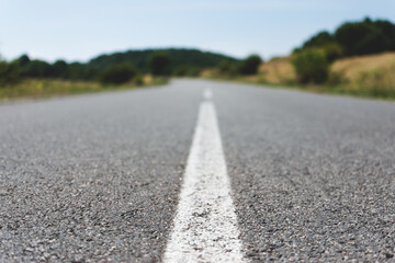 White dividing line on asphalt in nature. Road between hills or mountains