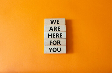 Help symbol. Wooden blocks with words We are here for you. Beautiful orange background. Business and We are here for you concept. Copy space.