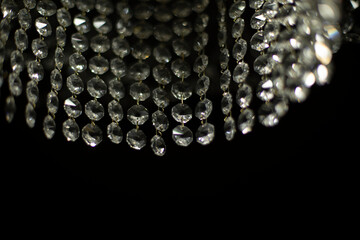 Crystal chandelier on black background. Interior details. Light in room. Light source. Glass sticks.