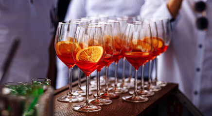 Glasses of alcoholic Aperol Spritz cocktail. Italian aperitif with ice, aperol, prosecco, soda and slice of orange in large round glasses on party. Celebration concepts festive days.