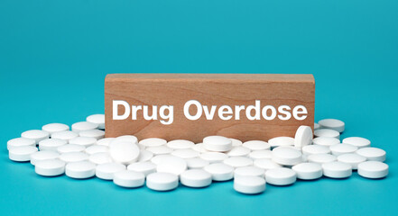 Drug overdose word on wooden block with white tablets on blue background. concept overdose for...