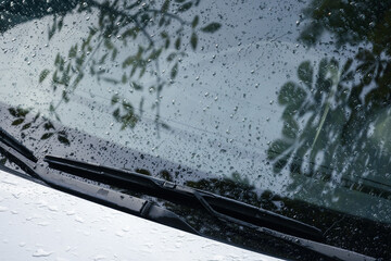 Car wipers and windshield with raindrops on it, closeup