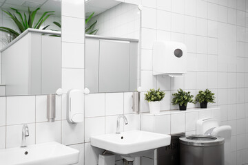 Toilet hand wash area with white colour ceramic tiles. White colour theme toilet interior. Cleanliness concept - obrazy, fototapety, plakaty