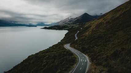 Aerial view of a mountain road by a lake in gloomy weather in New Zealand
