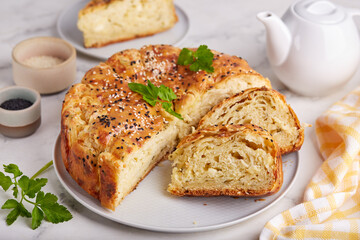 Savory layered pie from yeast dough with mozzarella and feta cheese, parsley and sesame seeds.