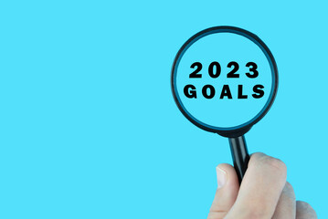 Focused on goals for next year 2023 concept. Words 2023 goals under magnifying glass. Card design.