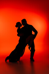 Side view of silhouette of couple dancing tango on red background - obrazy, fototapety, plakaty