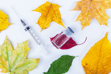 Autumn vaccination of population. Syringe in autumn leaves. Vaccination in autumn. New vaccine.