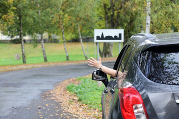 Dłoń kobiety, ręka wysunięta przez okno samochodu osobowego, suwa, na drodze, znak obszar...