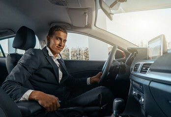 Young male businessman in a car rental service. Test drive concept. Blurred background