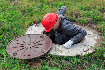 A male plumber in a helmet descended into an open water well for inspection and repair.