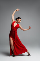 Woman in red dress and heels dancing on grey background