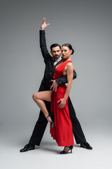 Full length of professional ballroom dancers looking at camera on grey background