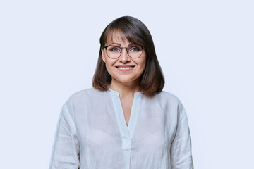 Smiling middle aged female looking at camera on light studio background