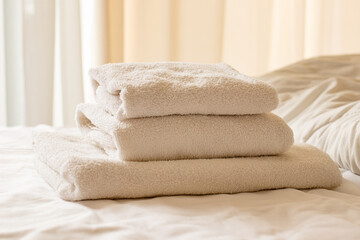 Clean towels on bed at hotel room. Bed maid-up with clean white pillows and bed sheets in beauty bedroom. Close-up