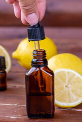 Lemon essential oil. Brown glass bottle, pipette with lemon oil and lemons on a wooden table