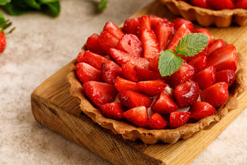 Delicious strawberry pie, dessert with fresh strawberries, mint leaves. Close up. Cupcake, tart on wooden board.