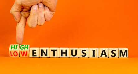 High or low enthusiasm symbol. Concept words High enthusiasm and Low enthusiasm on wooden cubes. Businessman hand. Beautiful orange background. Business high or low enthusiasm concept. Copy space.