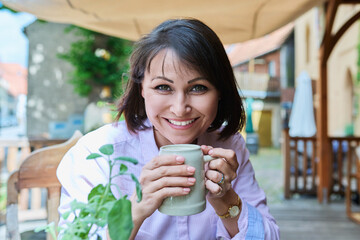 Middle aged happy woman with ceramic beer mug in german outdoor pub