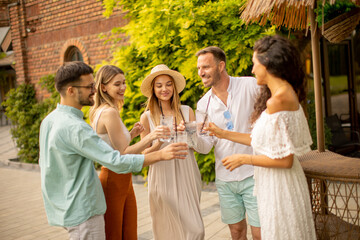 Group of young people cheering and having fun outdoors with drinks