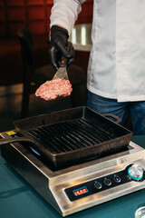 chef frying a hamburger patty in a frying pan