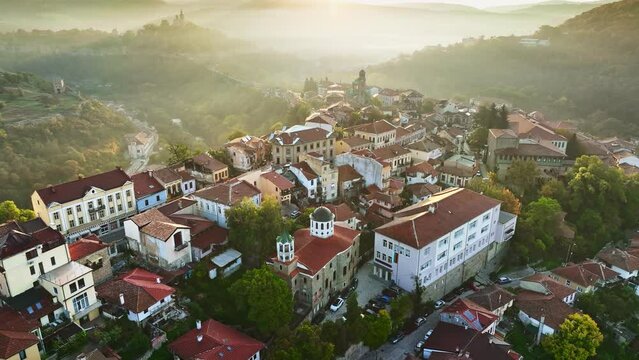 Aerial shot of sunny slightly foggy morning in Veliko Tarnovo, Bulgaria. Flying over old houses, Ascension Cathedral and river in the canyon in Veliko Tarnovo