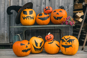 Bright orange pumpkins with painted black faces and bats like jack-o-lanterns on wooden wall background as Halloween's symbols