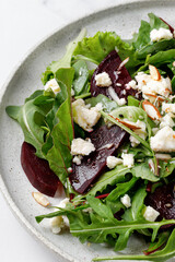 Vegetarian salad with beet, mix salad leaves, feta cheese, nuts. Meal healthy snack copy space for text. Isolated on marble white background.
