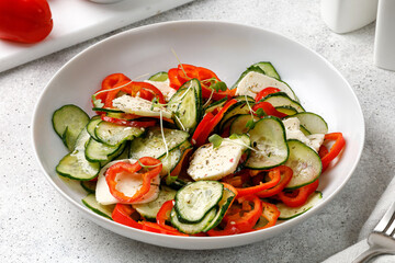Diet organic healthy Sliced salad with feta cheese, cucumbers, sweet peppers on white plate on grey background, Close up. Fresh dinner.