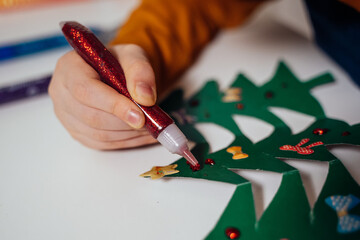 a boy decorates paper Christmas trees for Christmas