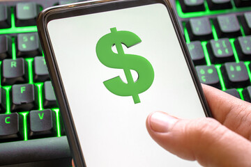 Smartphone with dollar symbol on screen phone with technology green colored keyboard background