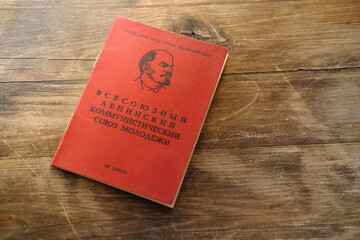 old personal document on wooden table, red Komsomol card, political youth organization, citizen of USSR middle of twentieth century, bureaucracy concept, family archive for social service