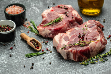 Pieces of raw pork steaks with rosemary and pepper on a dark background. banner, menu, recipe place for text, top view