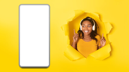 African Female In Headphones Near Big Smartphone Screen, Yellow Background