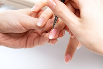 The master of the manicure coats nails with gel polish in the beauty salon. Professional care for...